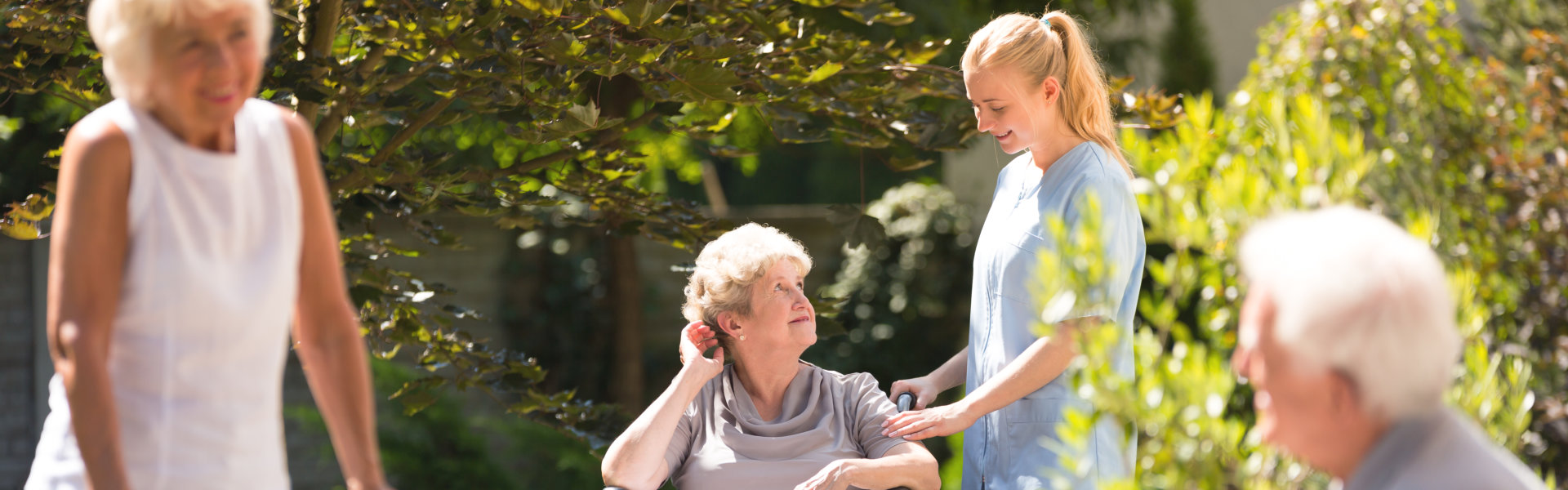 Elderly women in wheelchair spending time outside, getting some fresh air with her nurse